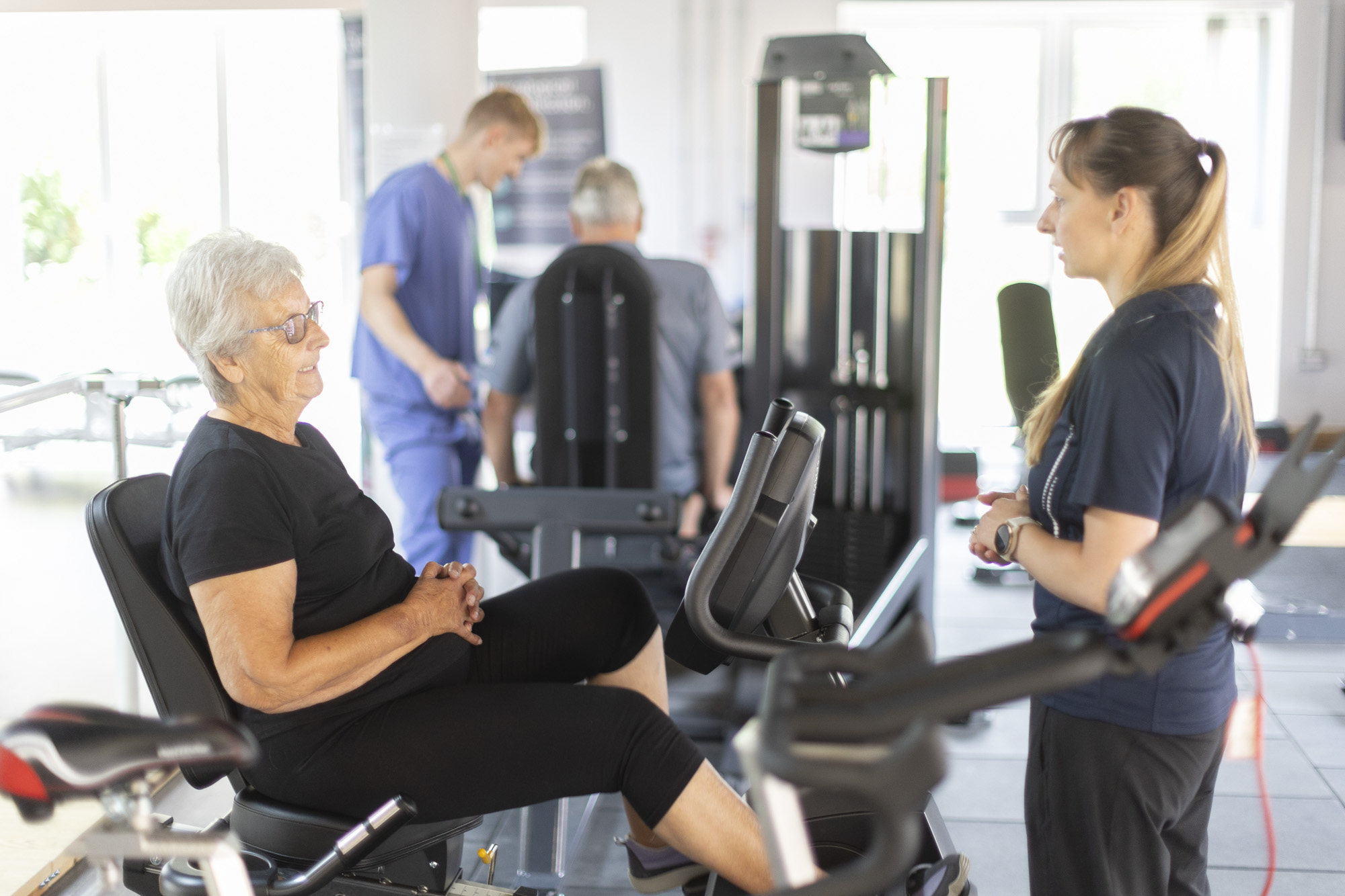 clinicians with their patients using exercise equipment