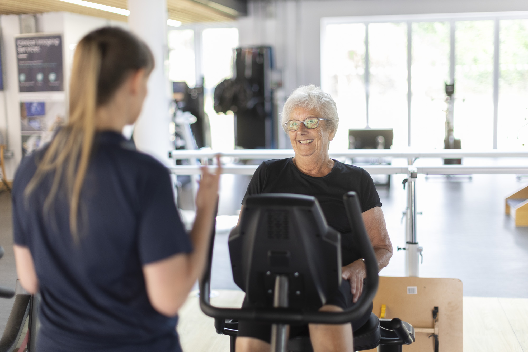 patient on exercise equipment and her physiotherapist providing guidance