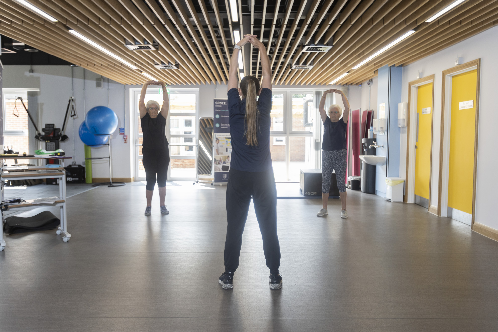 exercise class with three patients led by a physiotherapist