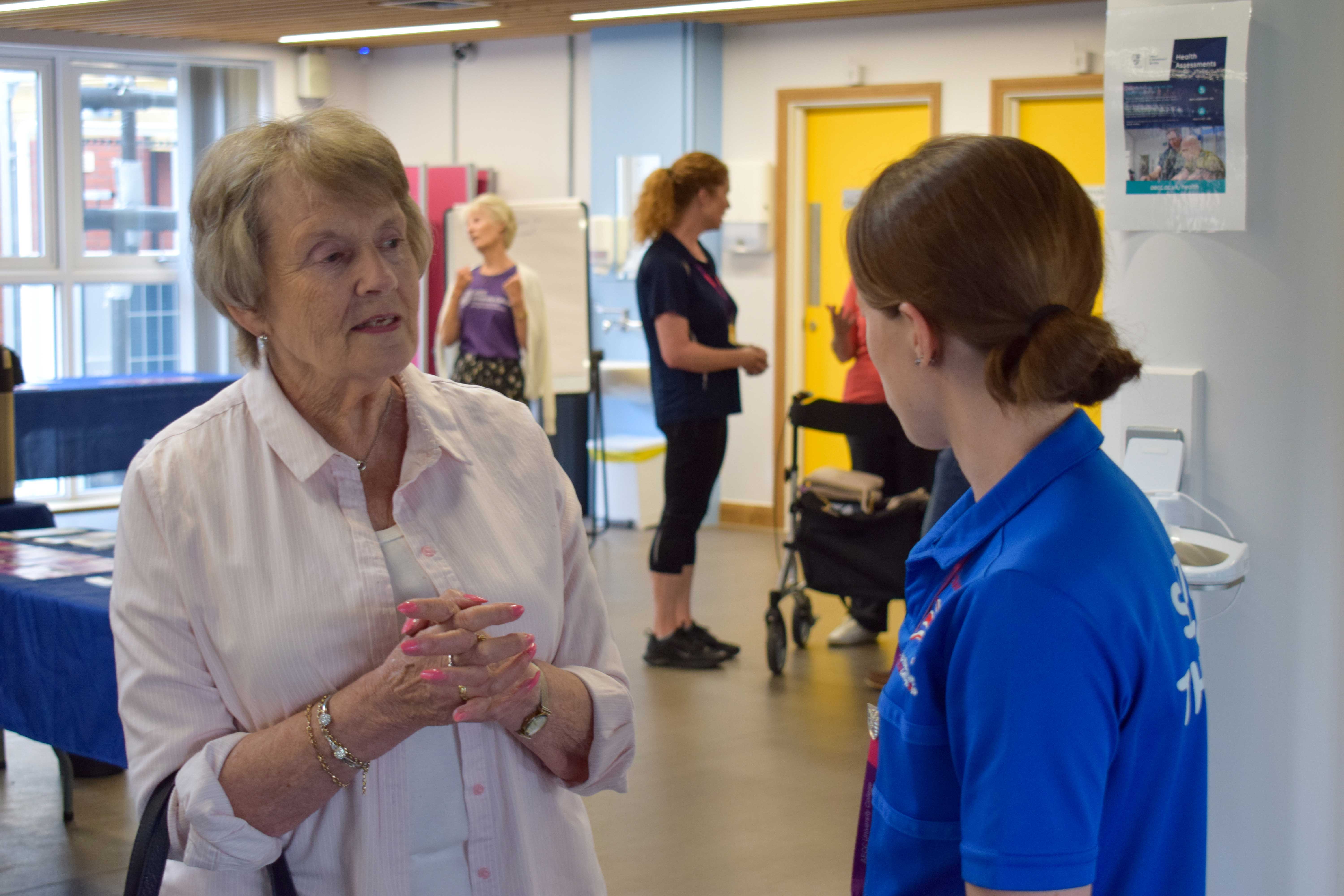 older woman and sports therapist in conversation about rehabilitation